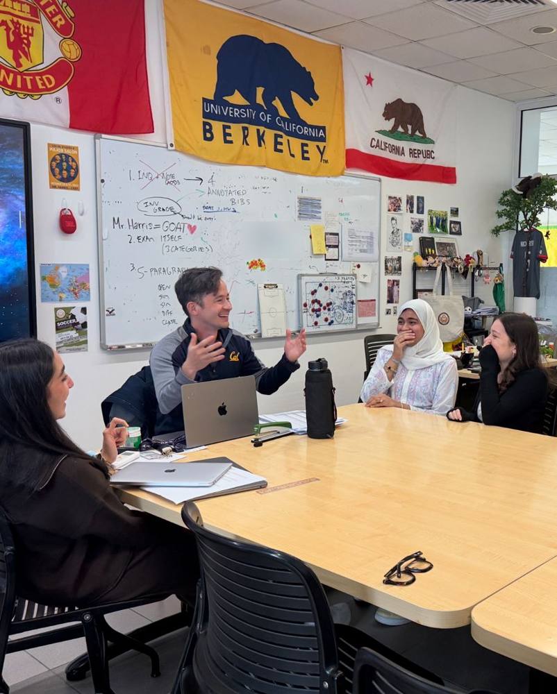 Nick laughing with AISR students around a classroom table