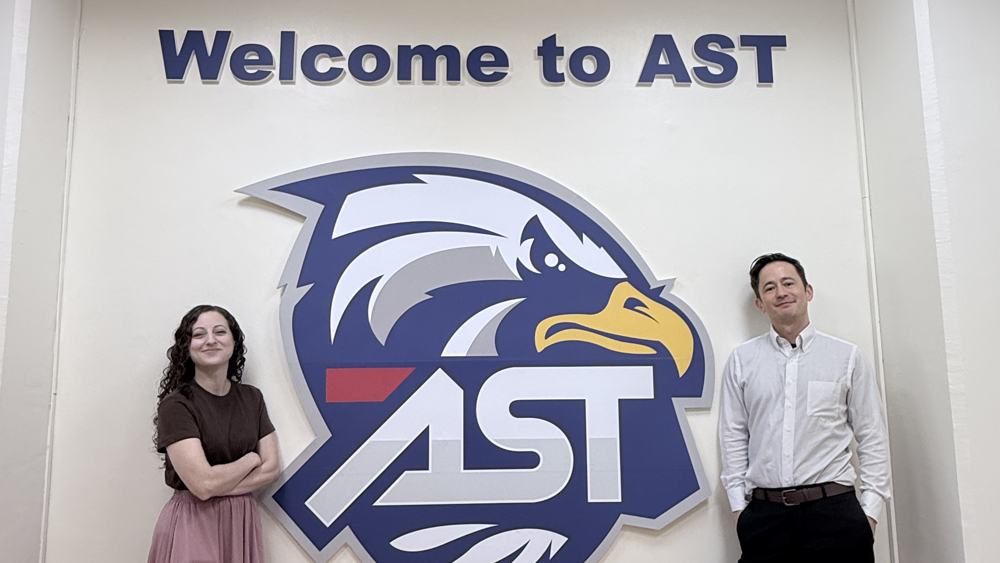 Nick and Sam under the Welcome to AST sign